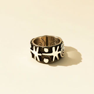 Decorative ring with black and silver design on a beige background