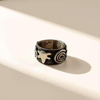 Decorative ring with star and spiral design on a light background