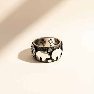 Silver ring with elephant design on a beige background