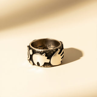Silver ring with engraved design on a beige background