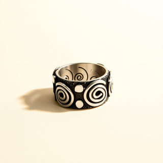 Ring with black and silver spiral pattern on a beige background