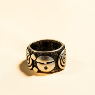 Silver and black ring with intricate designs on a beige background
