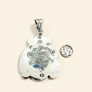 Silver  pendant with intricate designs on a beige background