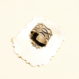 Silver ring shank with stamp 'Alex Sanchez Sterling' on a beige background