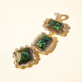 Three green stone pendant on a beige background.