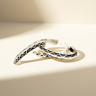 Three silver cuffs against an off-white background