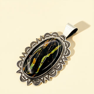 Silver pendant with black stone on a beige background