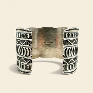 Silver cuff bracelet with geometric pattern on a beige background