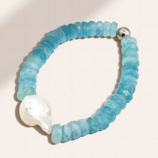 Blue beaded bracelet with a large white pearl on a light background