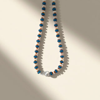 Necklace with blue, orange, and white beads on a beige background