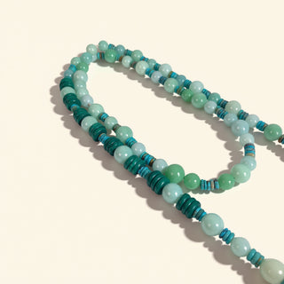 Beaded necklace with green and blue beads on a beige background