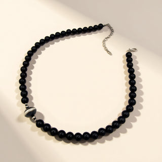 Black beaded necklace on a light beige background