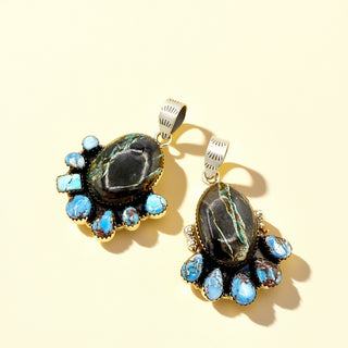 Pair of pendants with large central stones and smaller blue stones on a beige background