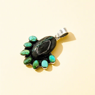 Jewelry pendant with green stones on a beige background