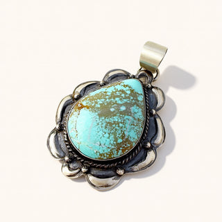 Turquoise stone pendant with silver frame on a white background