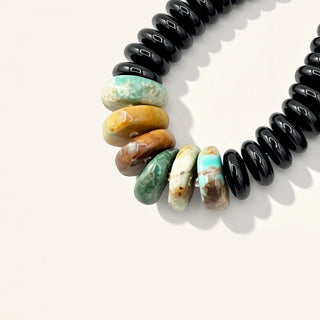 Beaded earrings with black, turquoise, and beige beads on a white background