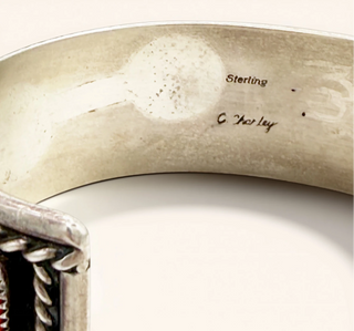Close-up of a silver bracelet with 'Sterling' and 'C. Challey' engraving on a white background