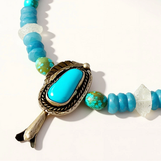 blue beaded necklace with pendant on a beige background