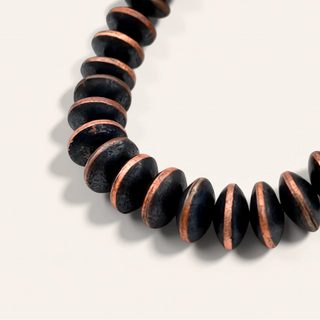 Black and copper beaded bracelet on a light gray background