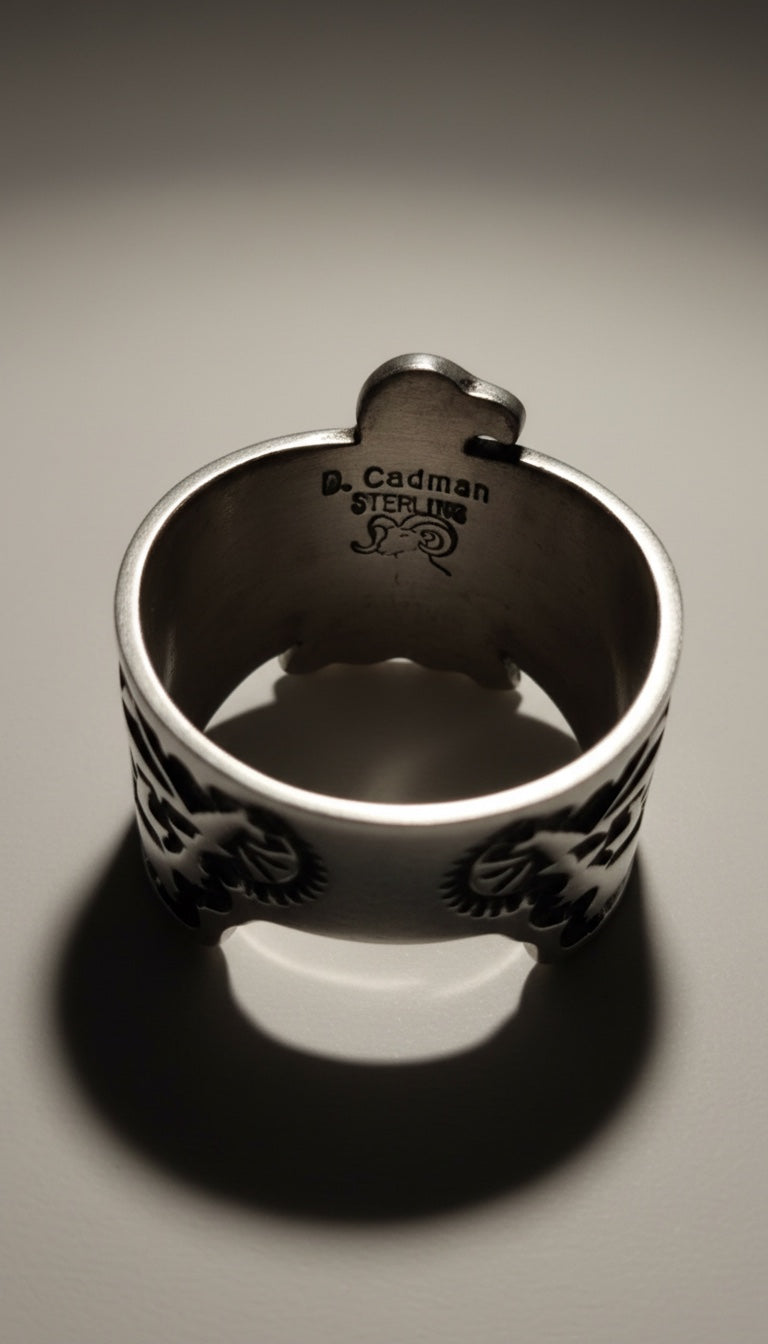 Silver ring with engraved design on a gray background