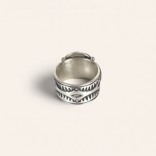Silver ring with tribal design on a light gray background