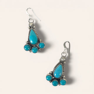Turquoise teardrop earrings with silver settings on a light gray background