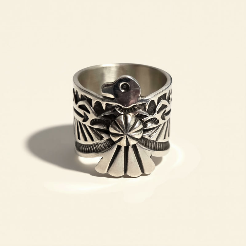 Silver ring with intricate design on a beige background