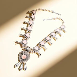 Ornate necklace with pink heart-shaped stones on a beige background
