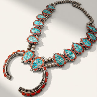 A Southwestern-style silver-toned necklace featuring turquoise and coral inlay, displayed on a clean off-white background.