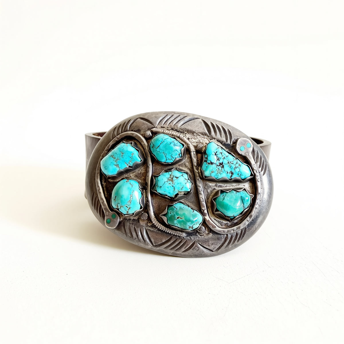 Silver belt buckle with turquoise stones on a white background