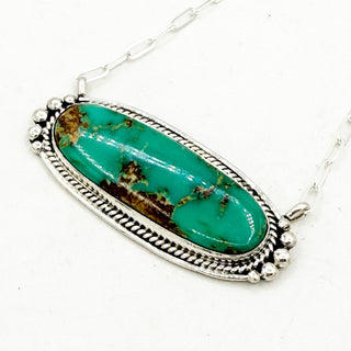 Turquoise stone pendant with silver framing detail on a white background
