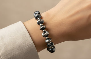 Silver beaded bracelet on a wrist against a beige background