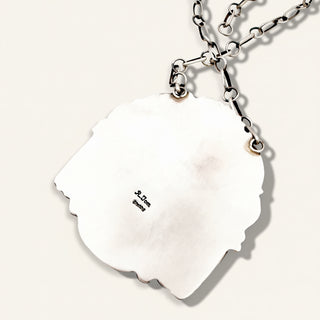 Silver necklace stamp 'R. Tom' on a beige background