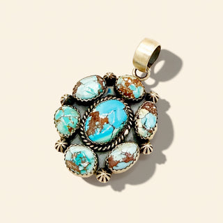 Turquoise stone pendant with silver accents on a beige background