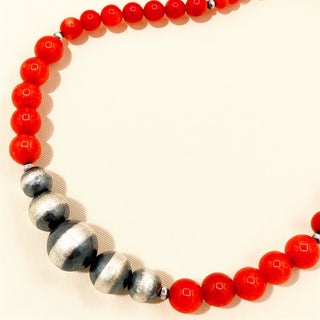Necklace with red beads and silver accents on a beige background