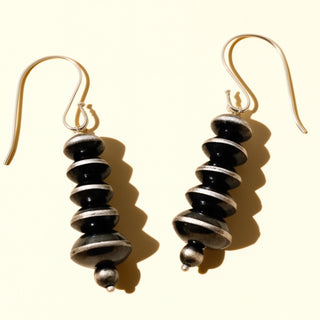 Pair of black earrings on a beige background