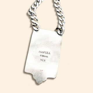 Silver chain necklace with a tag on a beige background