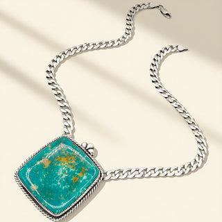 Silver necklace with a turquoise stone on a beige background