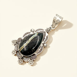 Silver pendant with black stone on a beige background