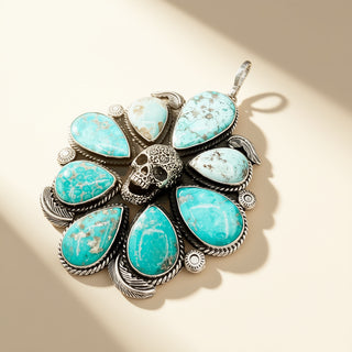 Silver pendant with skull and turquoise stones on a beige background