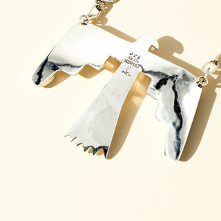 Silver bird necklace with 'JCV Hespera' stamp on a beige background