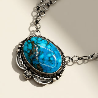 Necklace with a turquoise stone and silver chain on a beige background