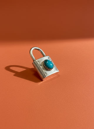 Silver padlock with a turquoise stone on an orange
