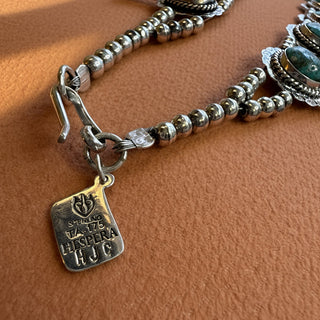 Silver necklace with a tag on a textured beige surface