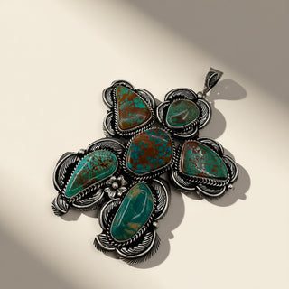 Silver pendant with turquoise stones on a beige background