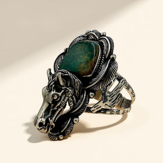 Silver horse head cuff with a green stone on a beige background