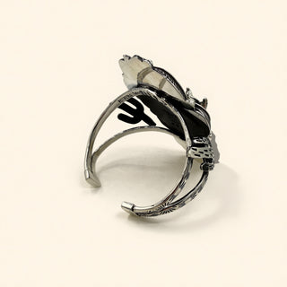 Silver cuff with black design on a beige background