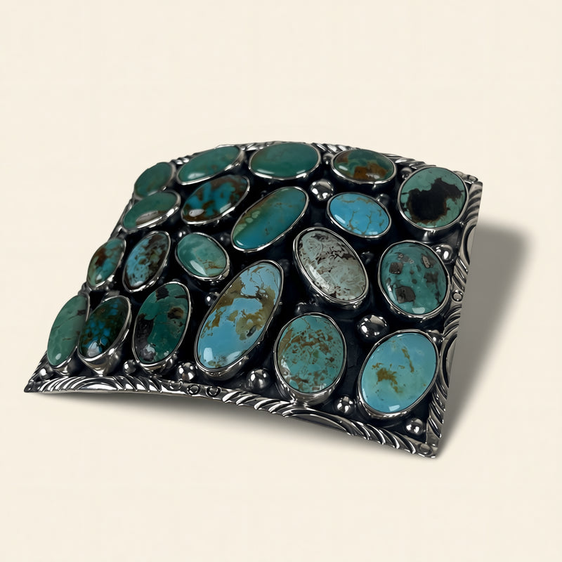Jewelry piece with turquoise stones and silver border on beige background