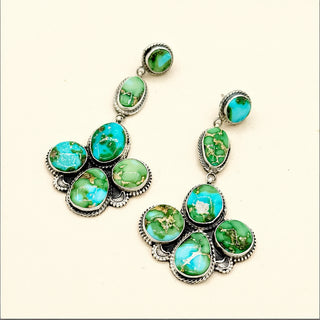 Marbled green and blue earrings against a beige background