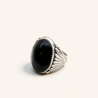 silver ring with a black stone on a beige background